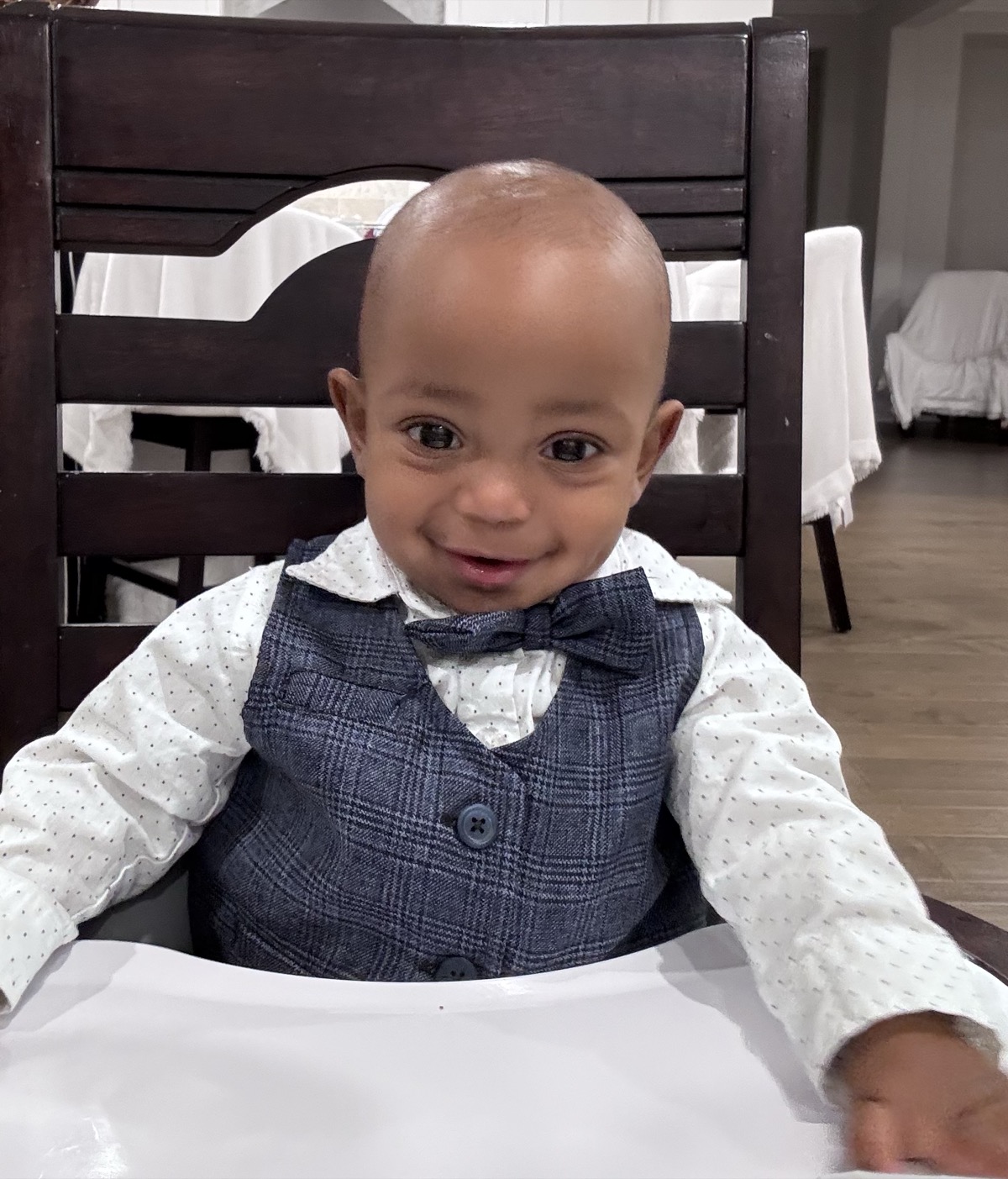 Baby Yohannes dressed up in a plaid vest, bow tie, and polka-dot dress shirt, sitting in a high chair looking dapper