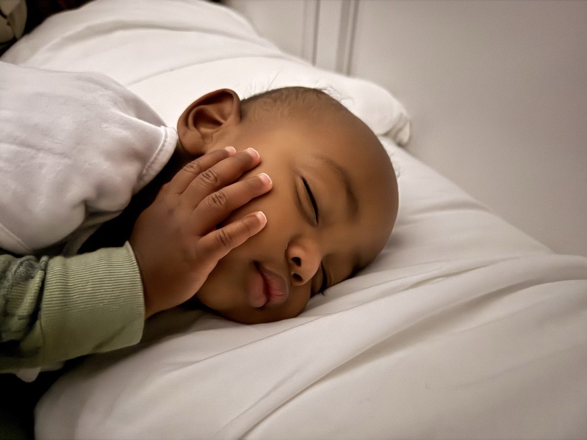 Baby Yohannes sleeping peacefully on white bedding with his hand resting gently on his cheek